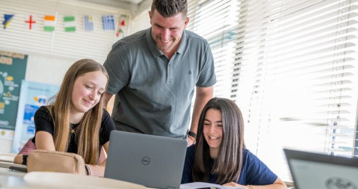 Docent lacht en helpt leerlingen